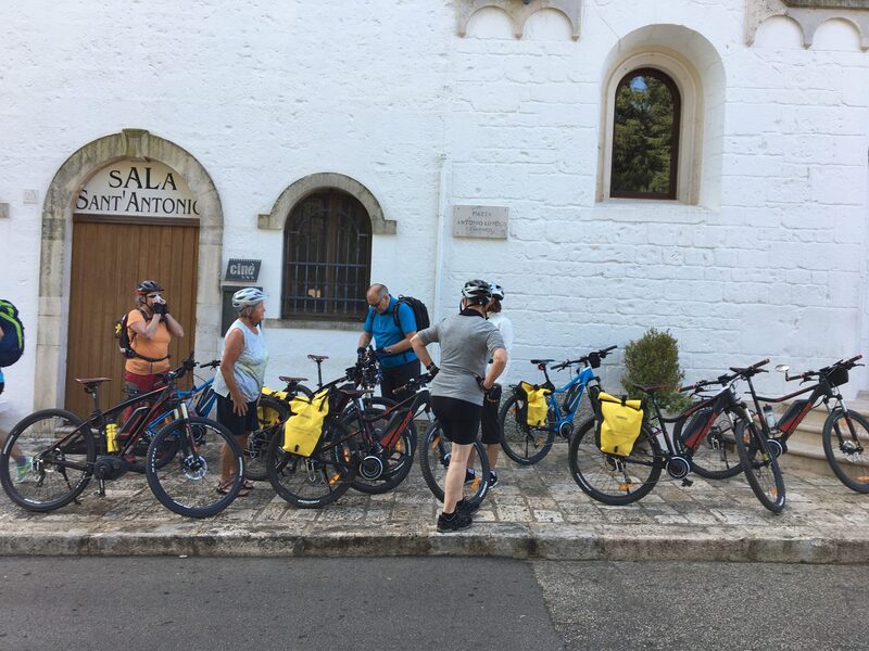 Radreisegruppe mit E-Bikes vor einer weiß getünchten Kirche in Alberobello im Itria-Tal